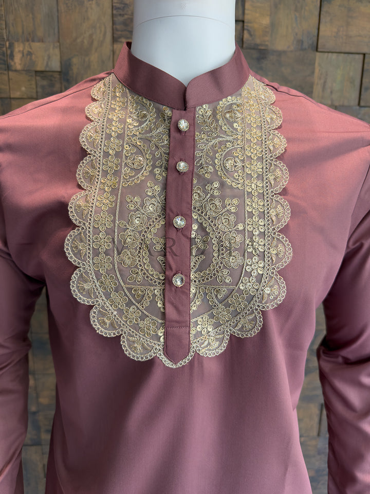 Mauve shirt with gold embroidery on a mannequin against a textured wall. Close-up of a designer Mauve Pink kurta highlighting the intricate Zari floral motifs, brilliant sequin highlights, and crystal-studded metallic buttons.