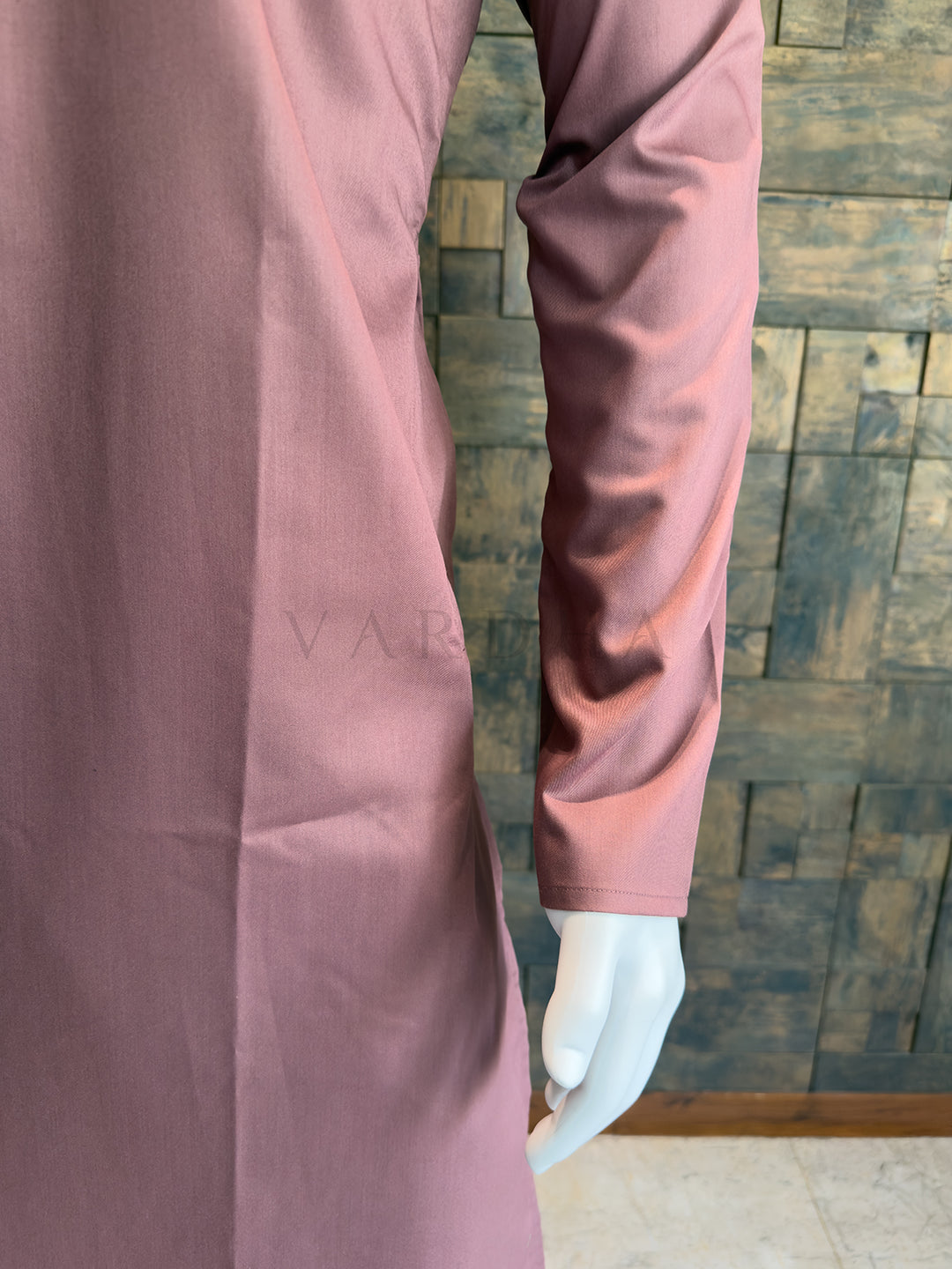 Mannequin wearing a pink long-sleeve dress against a wooden paneled wall. Premium Mauve Pink cotton kurta showcasing a smooth, formal drape and a highly breathable fabric finish ideal for long festive celebrations.