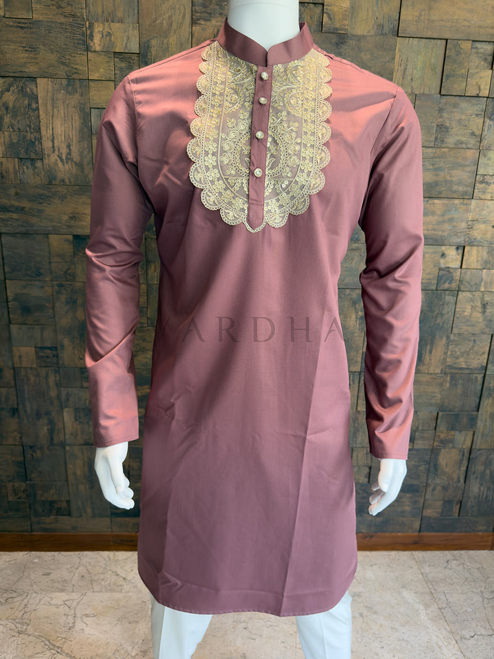 Mauve kurta with gold embroidery on a mannequin against a wooden paneled wall. Elegant dusty pink designer kurta for men, an impeccable choice for Sangeet nights and daytime weddings, featuring a crisp Mandarin collar.