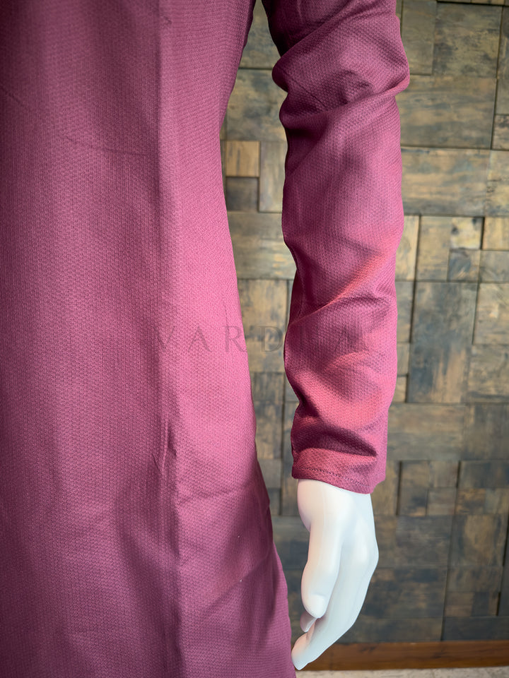Close-up of a person wearing a maroon long-sleeve shirt against a wooden paneled wall. Versatile Mauve Pink cotton kurta with a Mandarin collar; a sophisticated ethnic piece that pairs exceptionally well with white or cream pyjamas.
