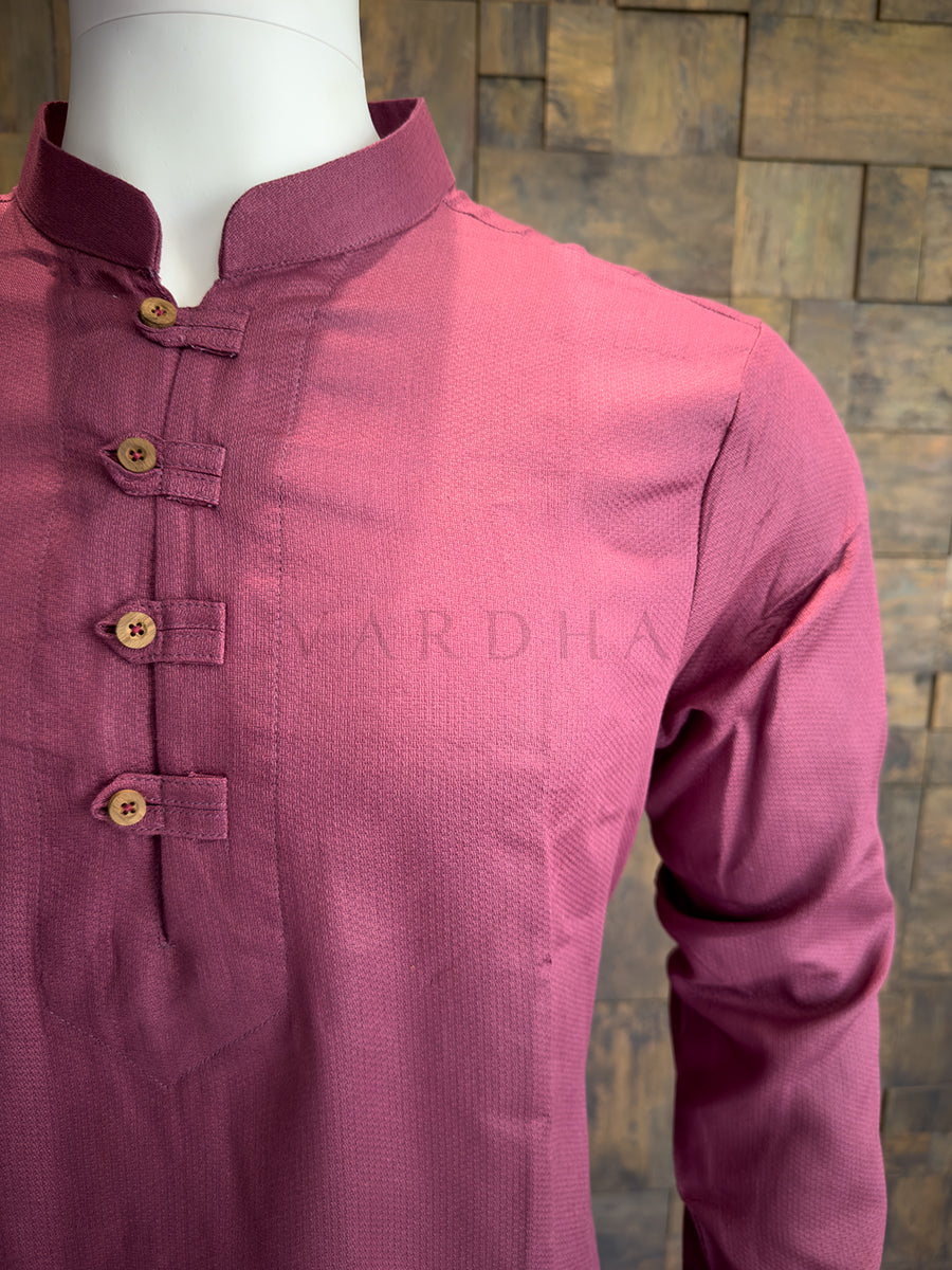 Mauve kurta with buttons on a mannequin against a wooden paneled wall.
