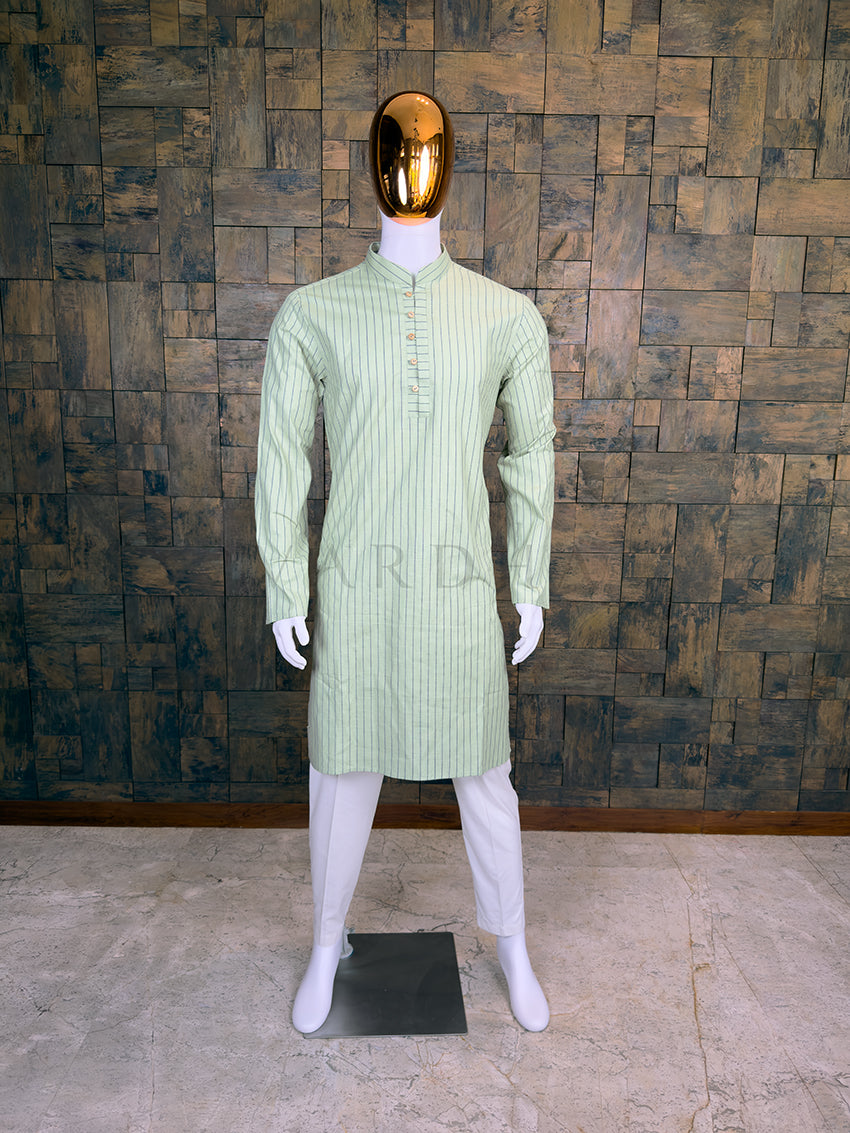 Mannequin wearing a light green kurta with white pants against a wooden paneled wall.
