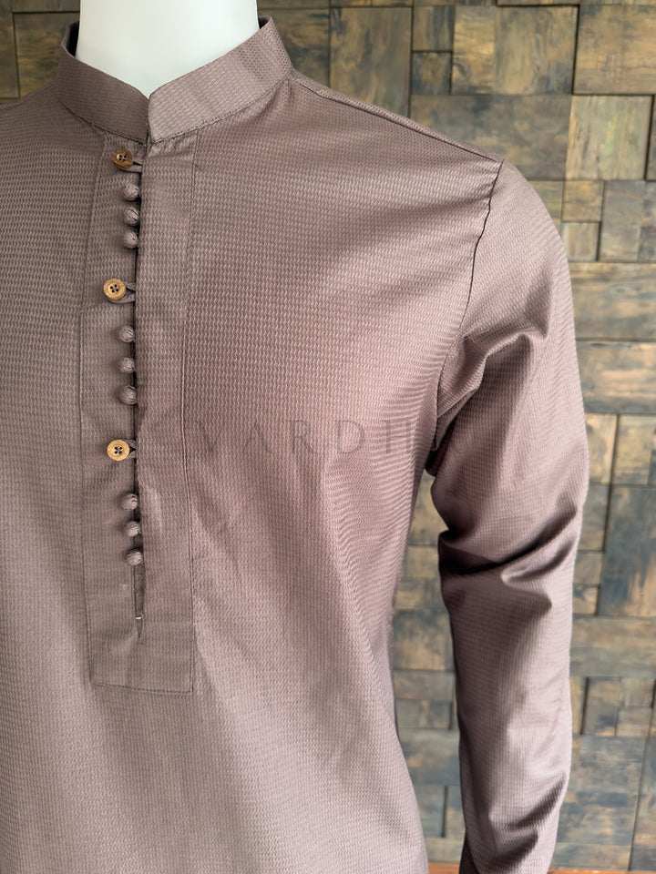 Brown textured shirt on a mannequin against a wooden paneled wall. Side angle of the tailored mocha cotton kurta for men, emphasizing the structured fit and subtle woven texture, ideal for sophisticated evening and day wear.