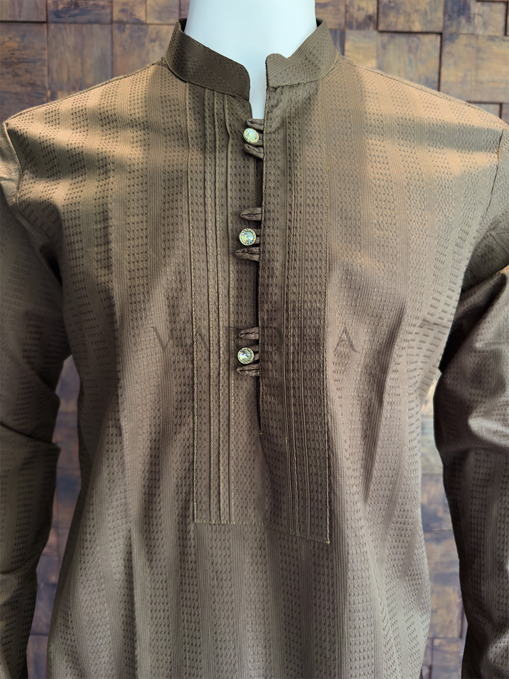 Brown textured shirt on a mannequin against a stone wall background. The woven texture enhances the fabric&