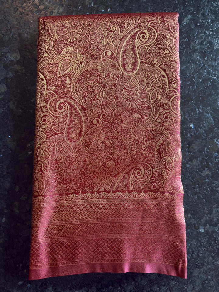 Folded view of the saree showing the heavy paisley zari pallu design. Texture shot showing the glossy sheen and smooth finish of the soft silk fabric.