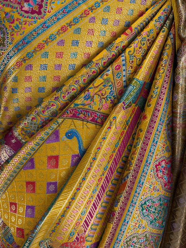 Colorful fabric with intricate patterns and designs Macro shot of a premium Meenakari silk saree fabric in gathered pleats, revealing highly detailed multi-color woven textures, a geometric diamond lattice pattern, and traditional Indian bird motifs seamlessly integrated into the weave.