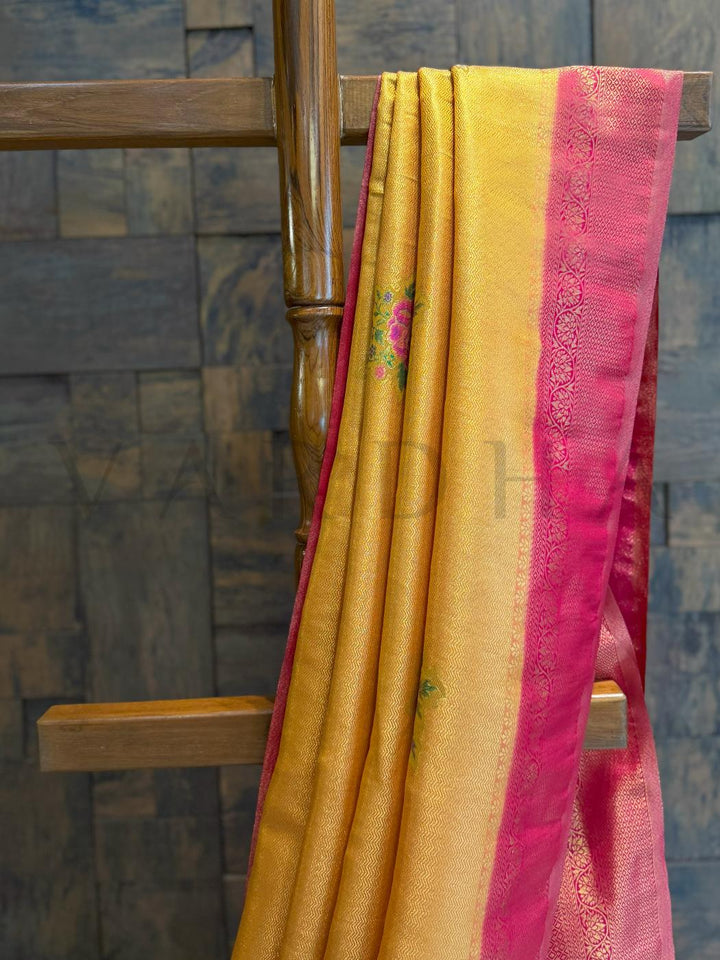 Pallu close-up revealing pink kalamkari floral work on rich silk backdrop with woven border., Golden border detail alongside mustard silk texture captured in soft daylight, ideal for festive dressing
