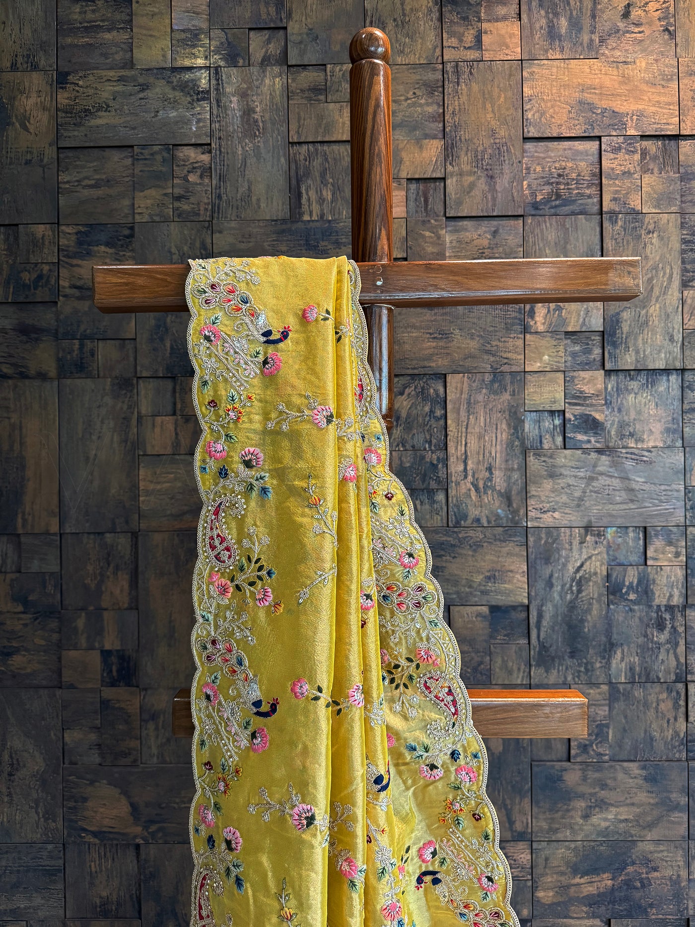Close-up of mustard tissue saree featuring multi-color floral and bird embroidery with sequins and zari highlights.