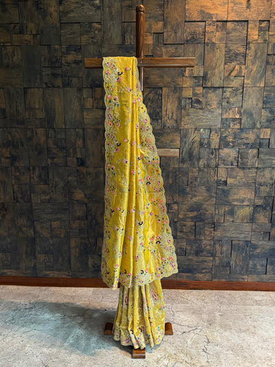 Full-length mustard embroidered saree in tissue silk with heavy embellished border and matching blouse piece.