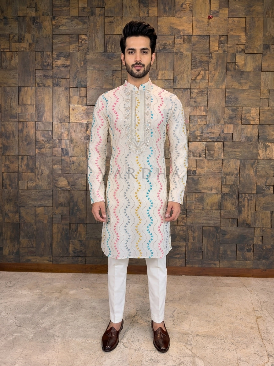  Off-White Pure Cotton Designer Kurta. Expertly crafted for comfort and style, this piece transforms breathable fabric into a festive statement. kurta features a rhythmic all-over wavy embroidery pattern, adorned with delicate leaf motifs in vibrant shades of Pink, Teal Blue, and Mustard Yellow. The design is highlighted by fine lines of silver sequins, adding a daytime sparkle that catches the sunlight. 