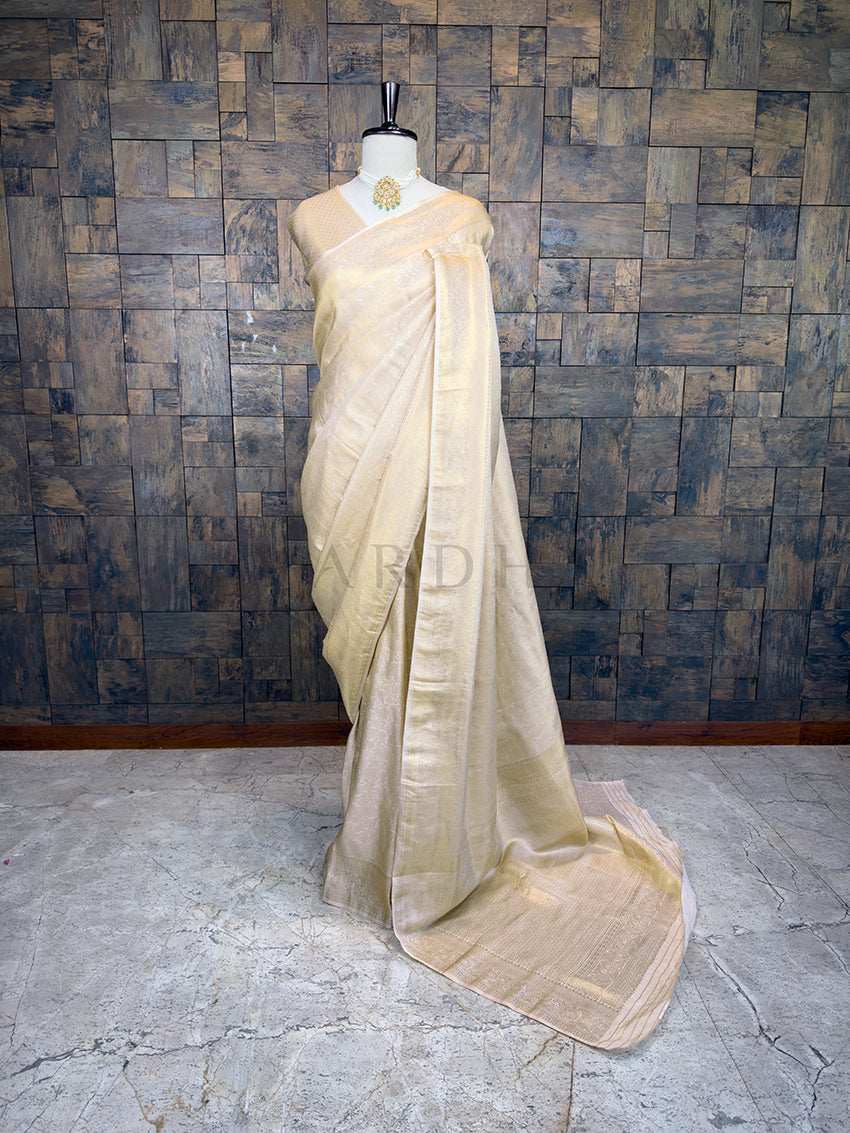 Beige saree on a mannequin against a textured wall. House of Vardha Off White Kanjivaram Silk Saree featuring an intricate Gold Zari Weave with traditional motifs, elegantly draped on a mannequin. We offer Ready to wear, Pre drape service, Saree Add on, Custom Stitched Blouse, Fall and Edging, Gift Packaging at Complimentary Price!