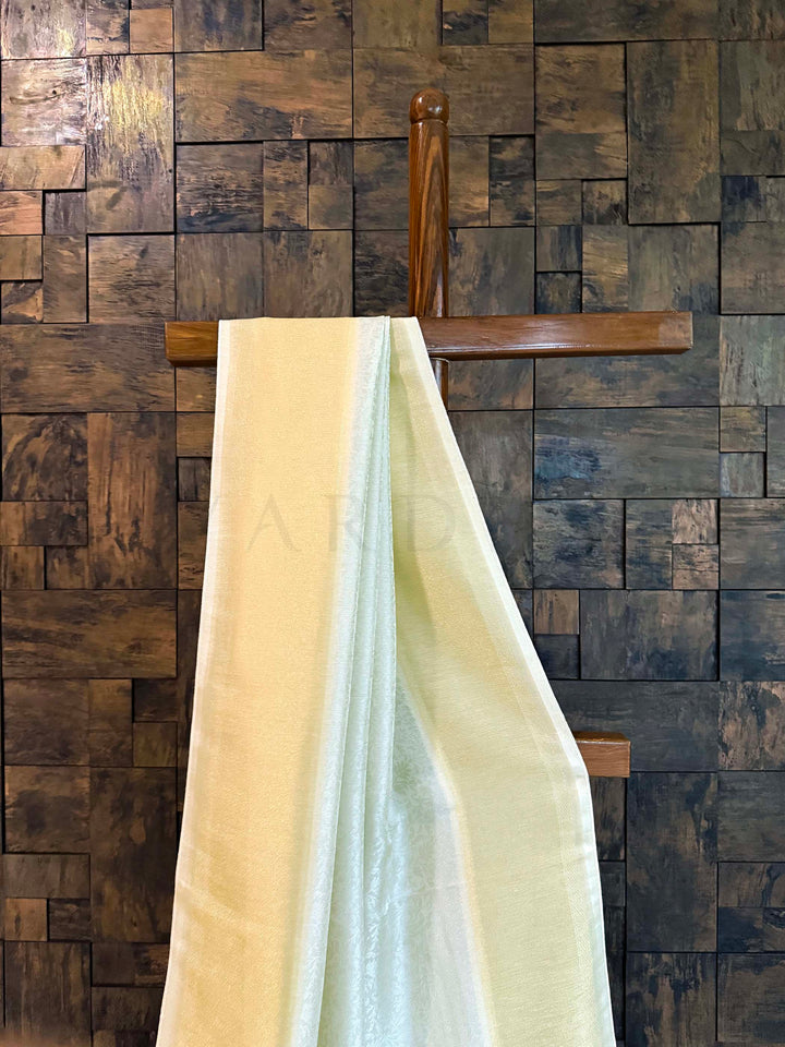 Wooden wall paneling with a draped fabric in front Pleats of pistachio-mint saree with gold border emphasizing fluid fall.