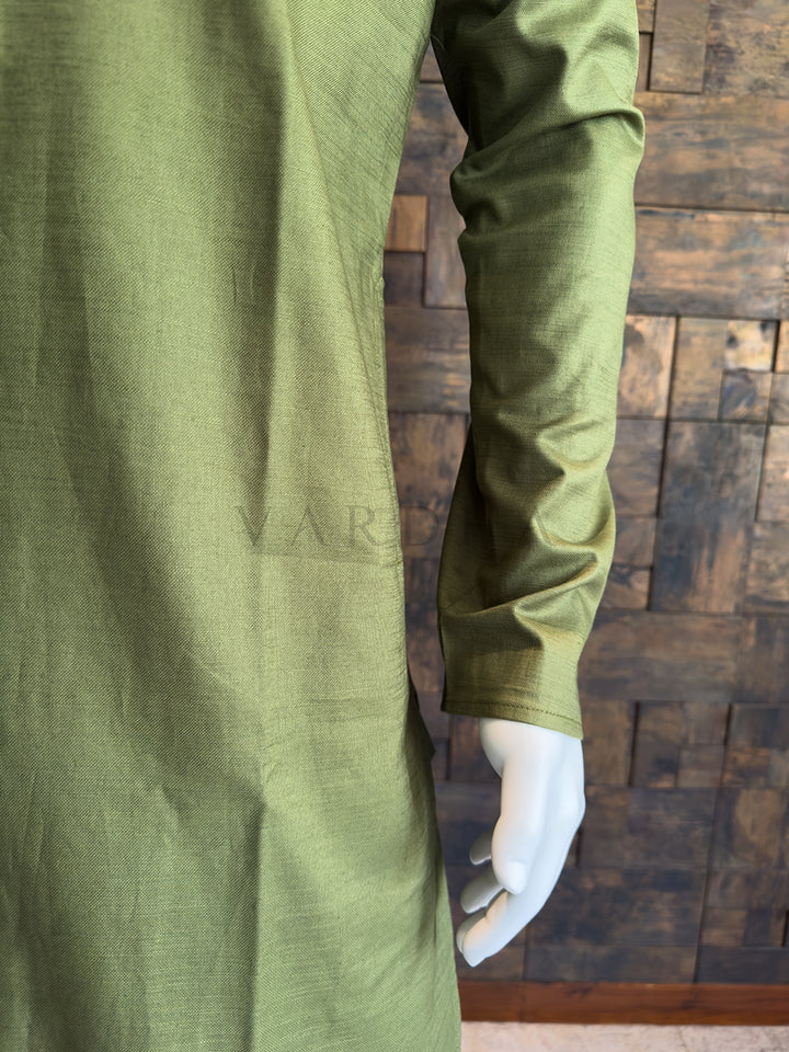 Green shirt on a mannequin against a wooden paneled wall Close-up of the subtle woven slub texture on the sleeve of the olive green cotton fabric.