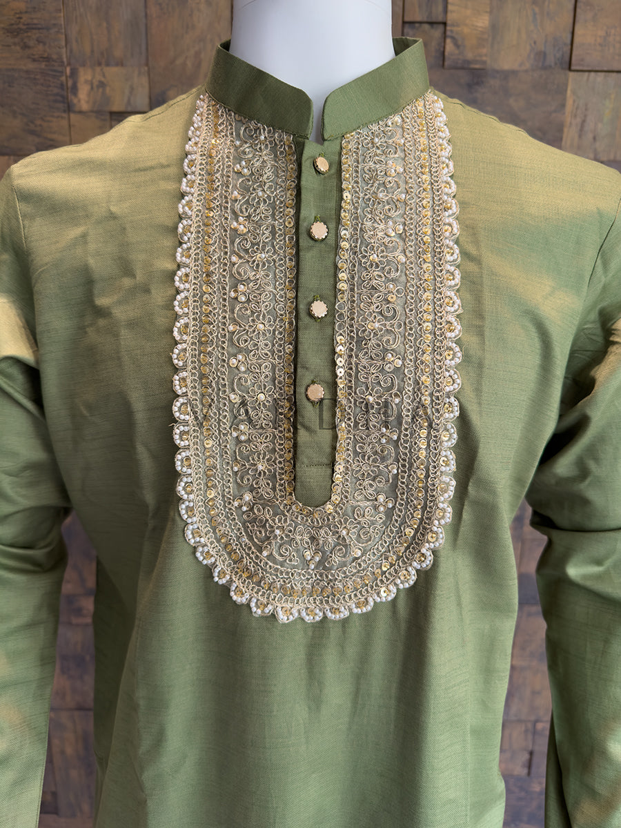 Green kurta with intricate embroidery on a wooden background. Close-up of an Olive Green designer kurta showing the intricate gold Zari embroidery and the aristocratic finish of a pearl-framed neckline.