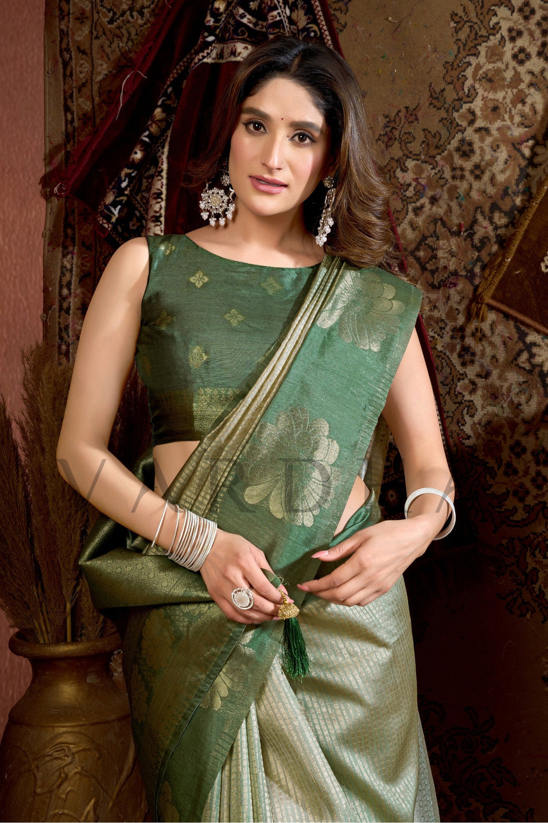 Woman wearing a green saree with a matching blouse against a decorative background Close-up view highlighting the luxurious sheen and soft texture of the Prijam Kota Silk fabric with matching blouse details.