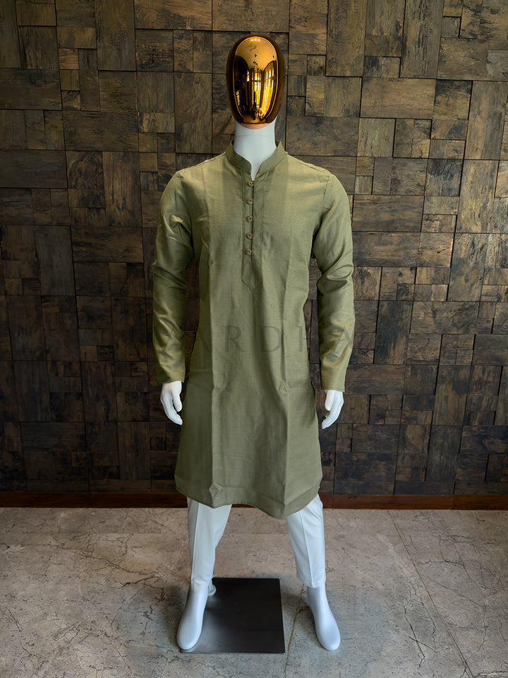 Mannequin wearing a green kurta with a gold mask against a wooden paneled wall. Modern earthy-toned men’s ethnic wear: A knee-length Olive Green kurta with a crisp, structured drape and a sharp Mandarin collar.