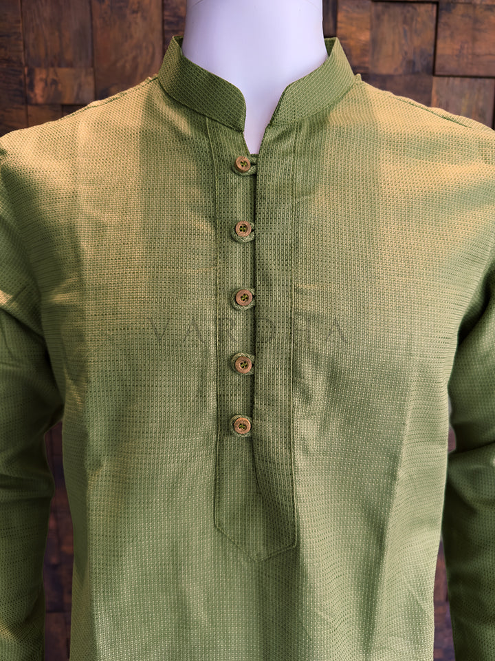 Green kurta on a mannequin against a wooden background. Modern earthy-toned men’s ethnic wear: A knee-length Olive Green kurta with a crisp, structured drape and a sharp Mandarin collar.