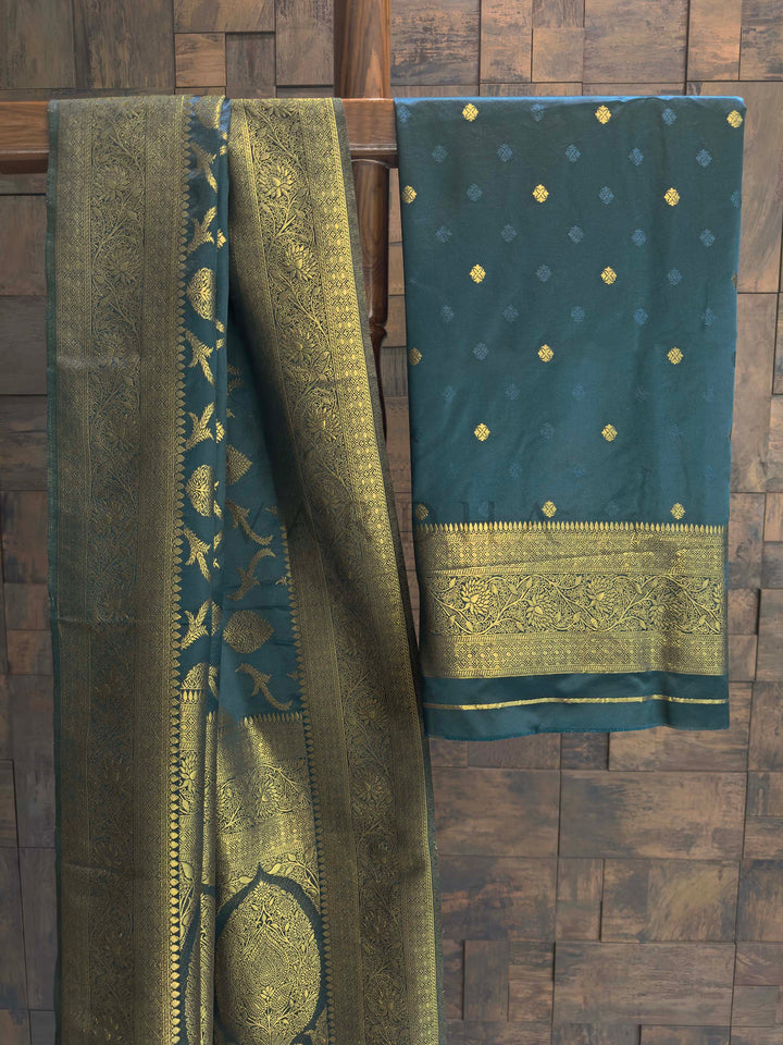 Peacock Blue Golden Zari Banarasi Satin Silk Saree House of Vardha. Exclusive House of Vardha Peacock Blue Golden Zari Banarasi Satin Silk Saree displaying an elaborate golden zari pallu and delicate motifs against a textured wall backdrop. We offer Ready to wear, Pre drape service, Saree Add on, Custom Stitched Blouse, Fall and Edging, Gift Packaging at Complimentary Price!