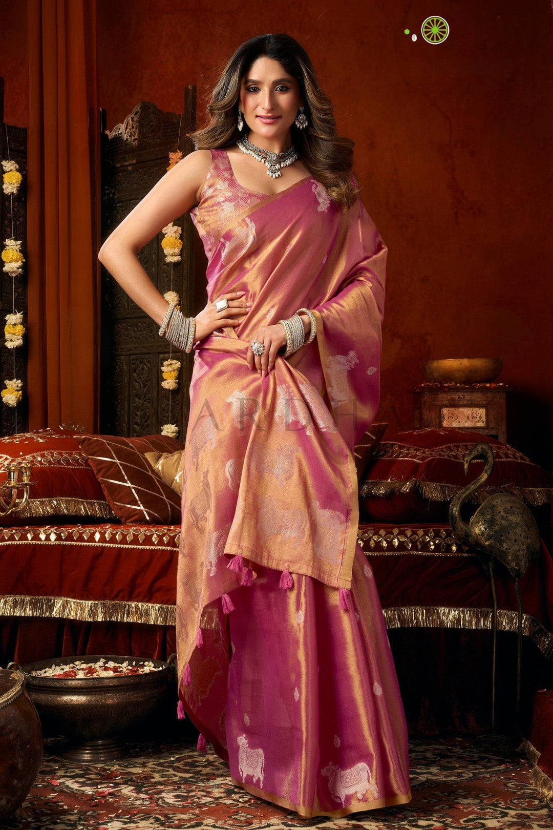Woman in a pink saree with a traditional setting Stylish front drape of the festive pink heavy tissue saree showing its metallic sheen, luxurious texture, and flawless fall.