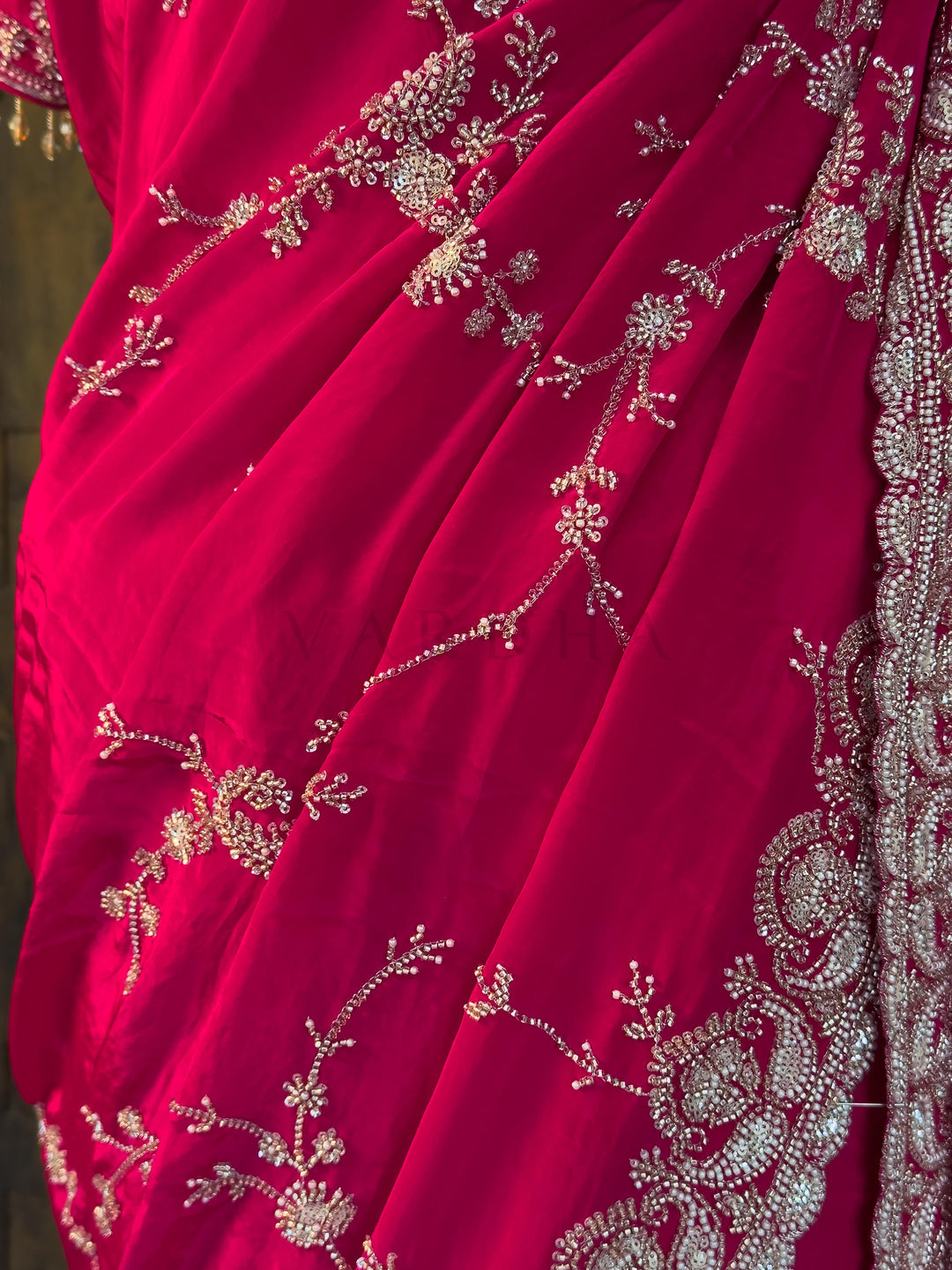 Close up of Delicate Silver Floral Vines and Cutdana Border. Beautifully draped Pink Satin Crepe Saree highlighting the smooth, elegant fall of the fabric and shimmering silver-toned embroidery by House of Vardha. We offer Ready to wear, Pre drape service, Saree Add on, Custom Stitched Blouse, Fall and Edging, Gift Packaging at Complimentary Price!