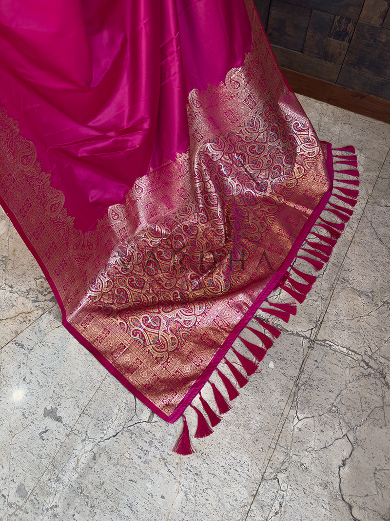 Pink saree with intricate patterns on a marble floor Detailed floor view of the rich, densely woven golden zari pallu with matching tassels on a vibrant pink satin saree. Elegant party wear rani pink satin silk saree highlighting its smooth drape, lustrous shine, and exceptional zari craftsmanship.
