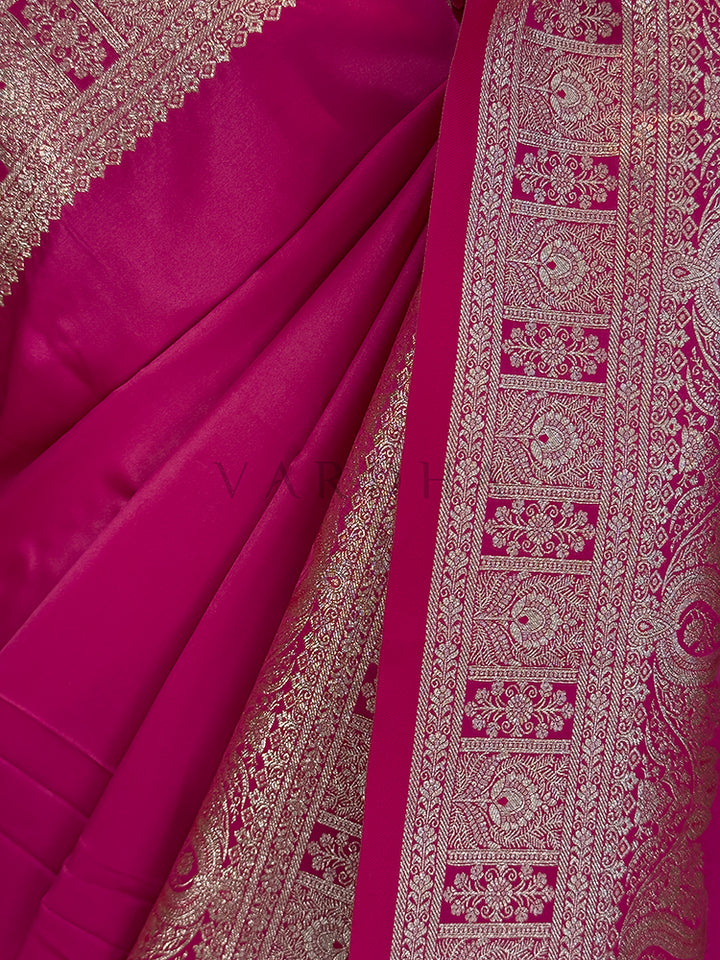 Close-up of a pink saree with intricate white patterns Close-up texture shot highlighting the solid glossy pink fabric contrasting with the intricate geometric floral zari border. Festive ethnic wear hot pink zari woven saree sweeping the floor, showcasing the heavily brocaded pallu and traditional patterns. Rich Indian wedding guest attire featuring a solid rani pink satin saree with opulent border details and traditional metallic weaving.