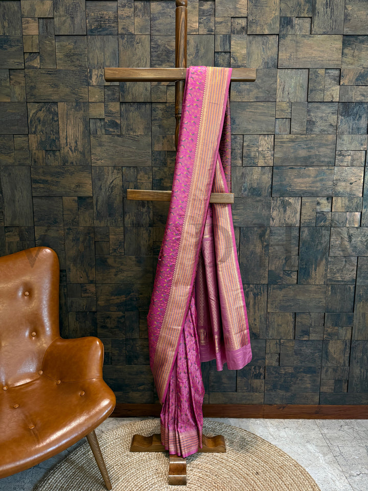 Full-length pink Tanchoi satin silk saree displayed with parrot motifs, golden zari striped border, and matching blouse piece