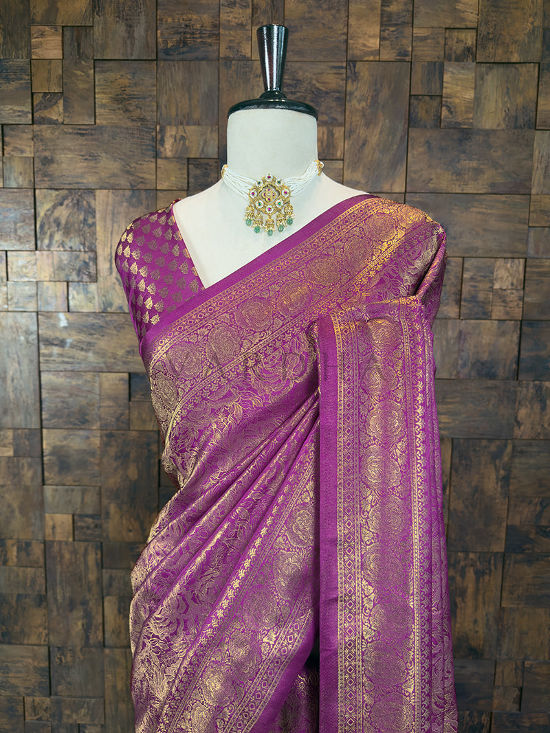 Close-up of the upper torso of a magenta Kanjivaram silk saree draped on a mannequin, highlighting the intricate golden zari floral motifs, detailed borders, and a matching blouse piece with golden diamond patterns.
