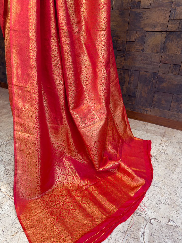 Red saree with intricate patterns draped over a textured surface. Red Silk Handloom Saree with Traditional Gold Threadwork, Bridal and Occasion Wear, House of Vardha