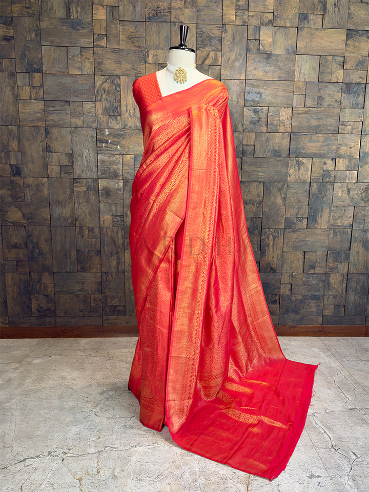 Red saree on a mannequin against a wooden paneled wall. House of Vardha Red Golden Zari Kanjivaram Silk Saree featuring heavy traditional gold woven motifs, draped on a mannequin.