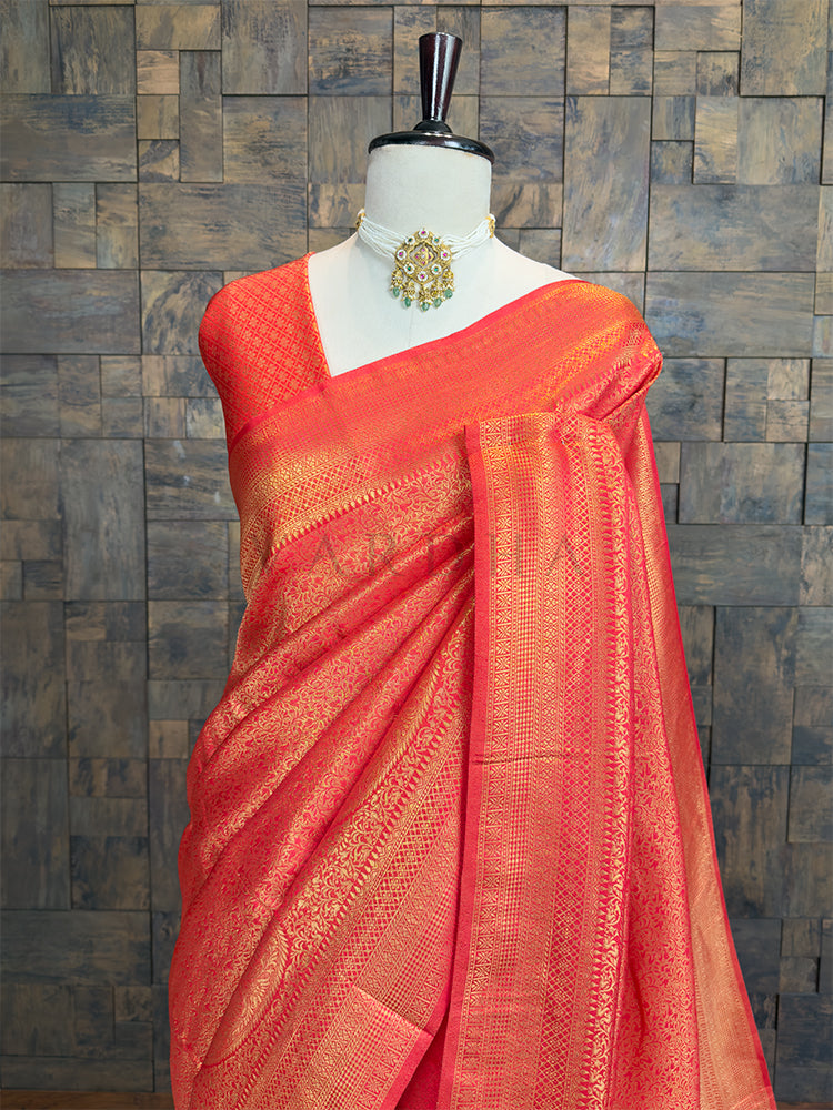 red saree with gold patterns on a mannequin against a textured wall. Luxurious authentic Kanjivaram Indian wedding saree in vibrant red from House of Vardha with extensive gold brocade.