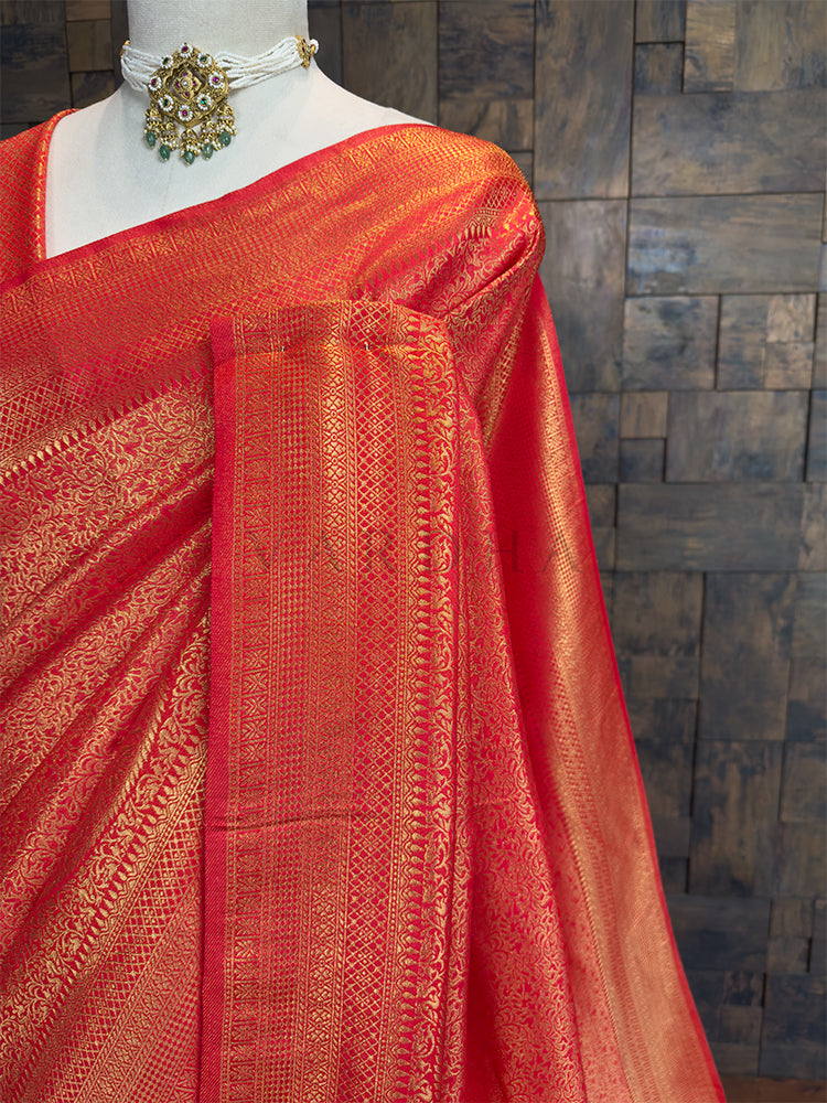 Red saree with gold patterns on a mannequin against a wooden paneled wall. Close-up of House of Vardha Red Golden Zari Kanjivaram Silk Saree highlighting the exquisite large gold zari paisley patterns on the pallu.