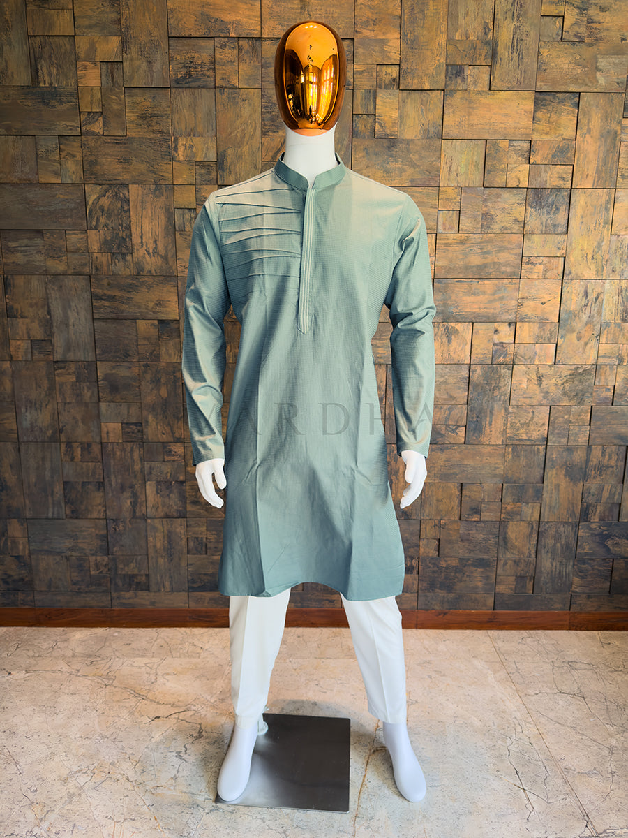 Front view of a man wearing a House of Vardha sage blue textured cotton kurta featuring asymmetrical pintuck pleats. Perfect men's ethnic wear for festive parties and traditional smart-casual events.