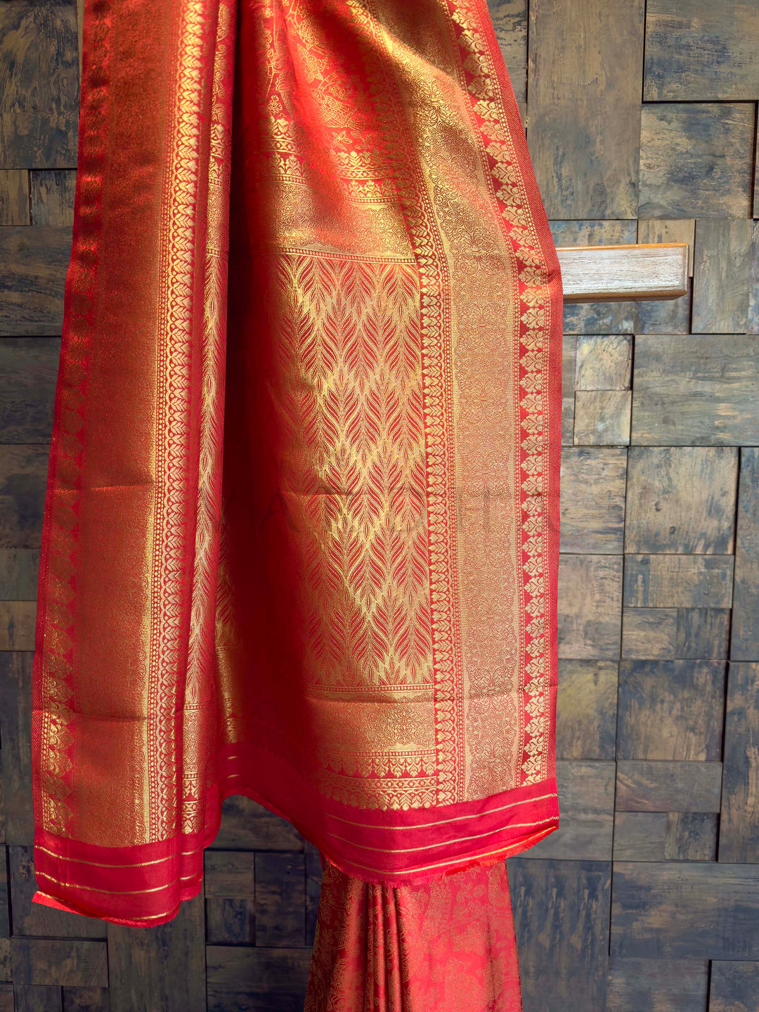 Red saree with gold patterns on a textured dark background Gold-woven bird motifs and vines on Sindoori red Kanjivaram silk fabric