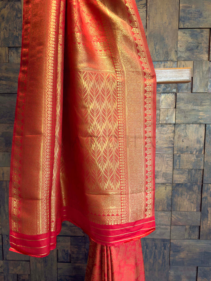Red saree with gold patterns on a textured dark background Gold-woven bird motifs and vines on Sindoori red Kanjivaram silk fabric