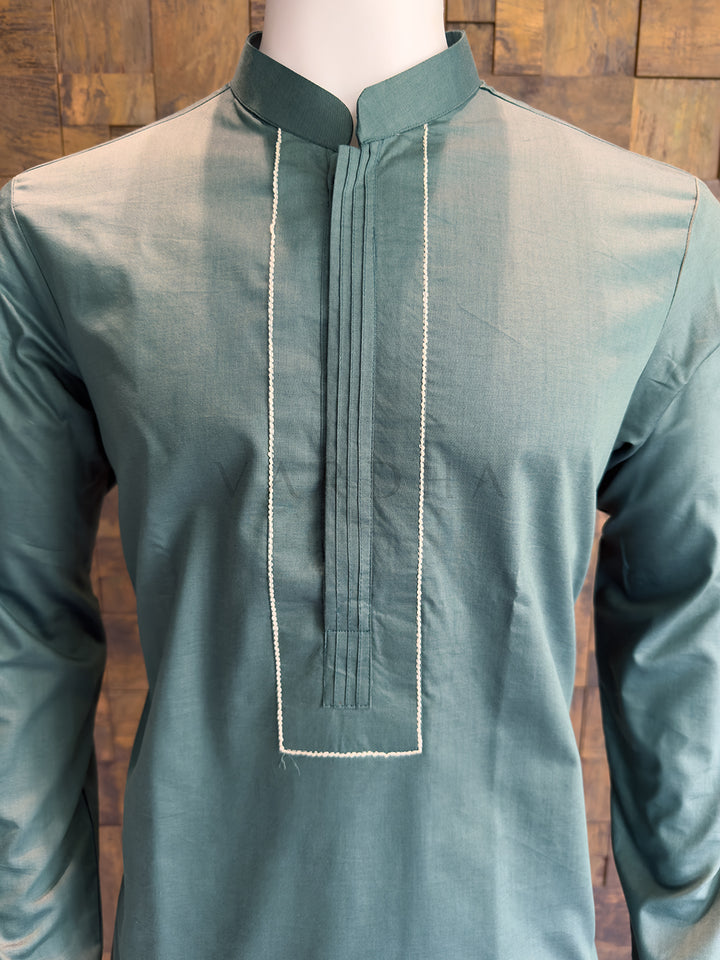 Green kurta on a mannequin against a wooden background. Close-up of a designer Slate Green kurta showing the seamless concealed button placket and the contrast rectangular stitched border on the chest.