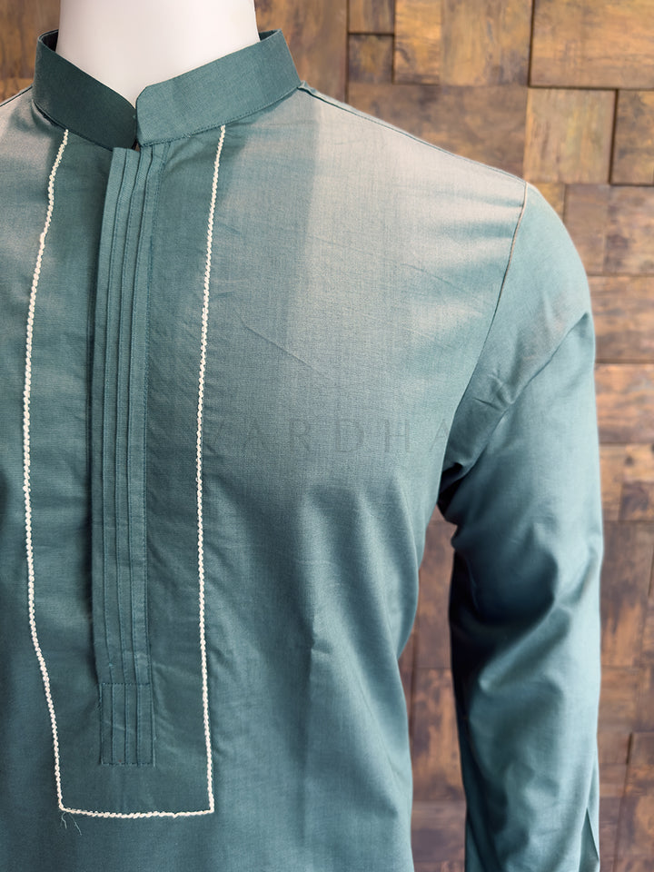 Green kurta on a mannequin against a wooden background. Detailed view of a Slate Green kurta chest featuring center vertical pintucks and a meticulously structured contrast frame.