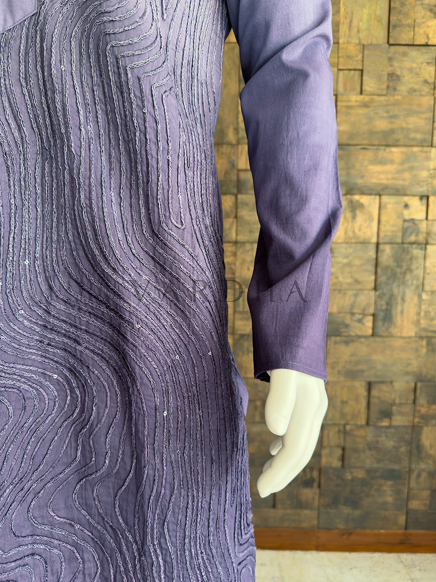 Mannequin wearing a textured purple dress against a wooden paneled wall. Side profile of the grey patterned viscose kurta for men, highlighting the luxurious drape, full sleeves, and detailed cord work for evening wear. Shop premium ethnic menswear for festive occasions and formal events.