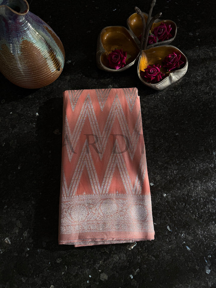 Folded pastel orange georgette saree with chevron patterns and elegant shimmer work, perfect for gifting