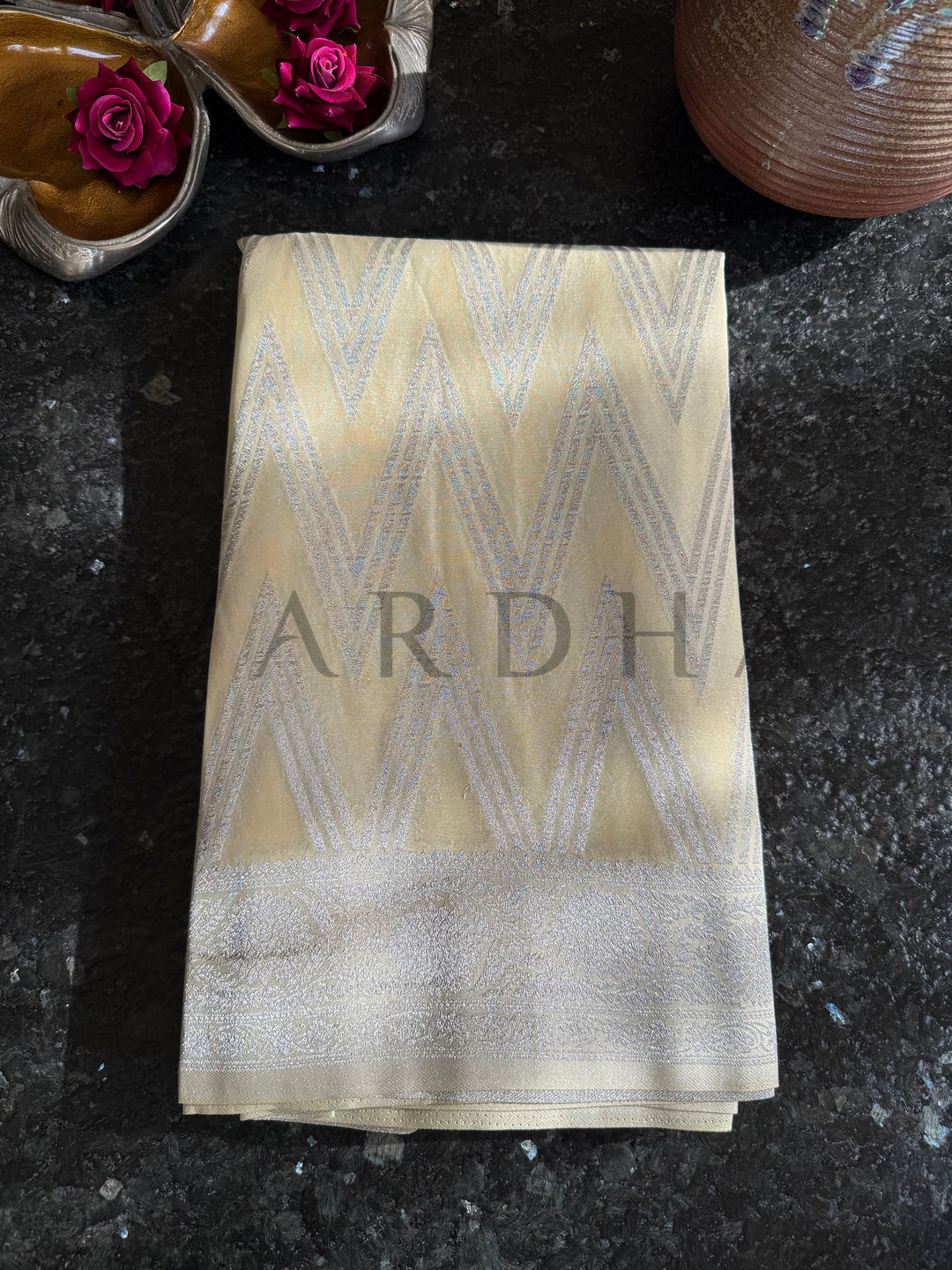 Folded soft yellow georgette saree featuring chevron patterns and subtle shimmer texture, ideal for pooja or gifting