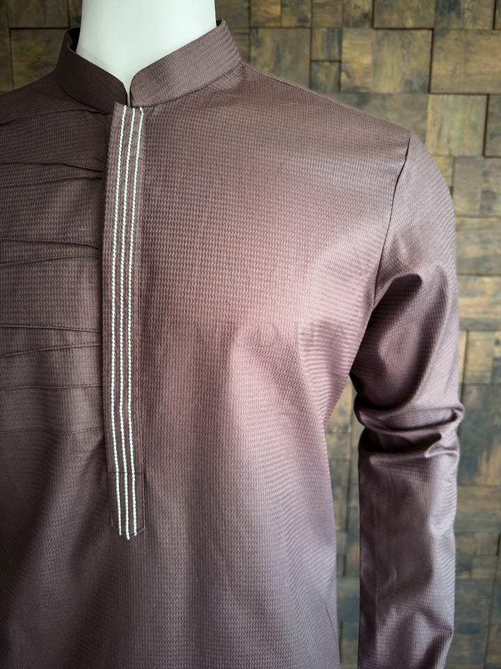 Brown textured shirt on a mannequin against a brick wall background. Side angle of the tailored brown cotton kurta for men, emphasizing the structured fit, woven texture, and modern asymmetrical chest design ideal for sophisticated evening wear.