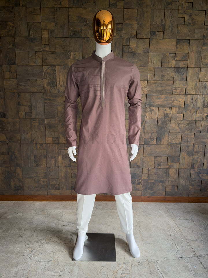 Mannequin wearing a Brown kurta with a gold mask against a wooden paneled wall. Front view of a man wearing a House of Vardha taupe brown textured cotton kurta featuring asymmetrical pintuck pleats. Perfect men&