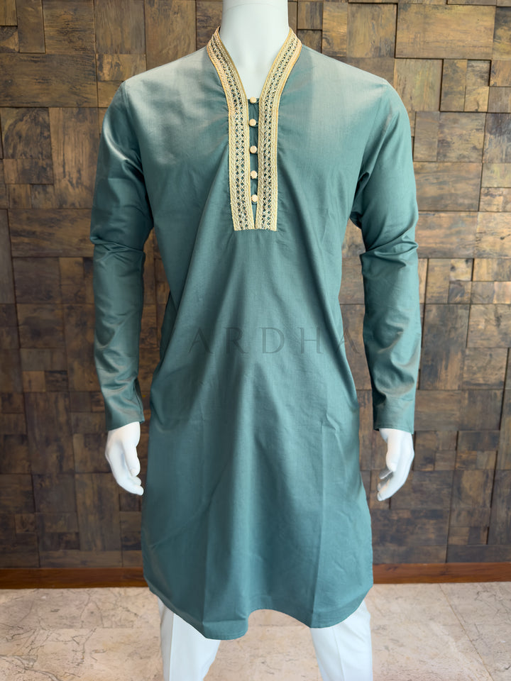 teal blue kurta with gold embroidery on a mannequin against a wooden wall. Elegant Teal Blue designer kurta for festive brunches and morning pujas, featuring a regal yet understated aesthetic with full sleeves.
