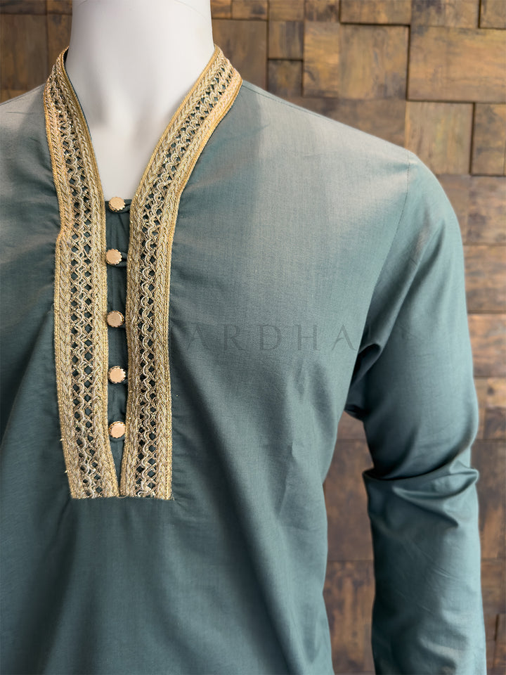 teal blue kurta with gold embroidery on a wooden background. Sophisticated Teal Blue collarless kurta with gold Zari detailing; an impeccable ethnic choice that pairs perfectly with white or cream pyjamas.