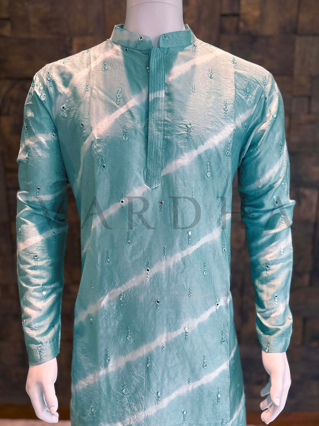 Teal kurta on a mannequin against a dark brick wall. Front panel detail highlighting shibori-style diagonal white stripes and tasteful sequin scatter that adds gentle sparkle for festive events.
