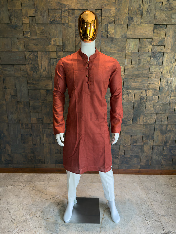 Mannequin wearing a rust-colored kurta against a wooden paneled wall. Close-up of a designer rust orange kurta showing the distinct micro-check fabric pattern and rustic, artisanal wooden-style buttons.