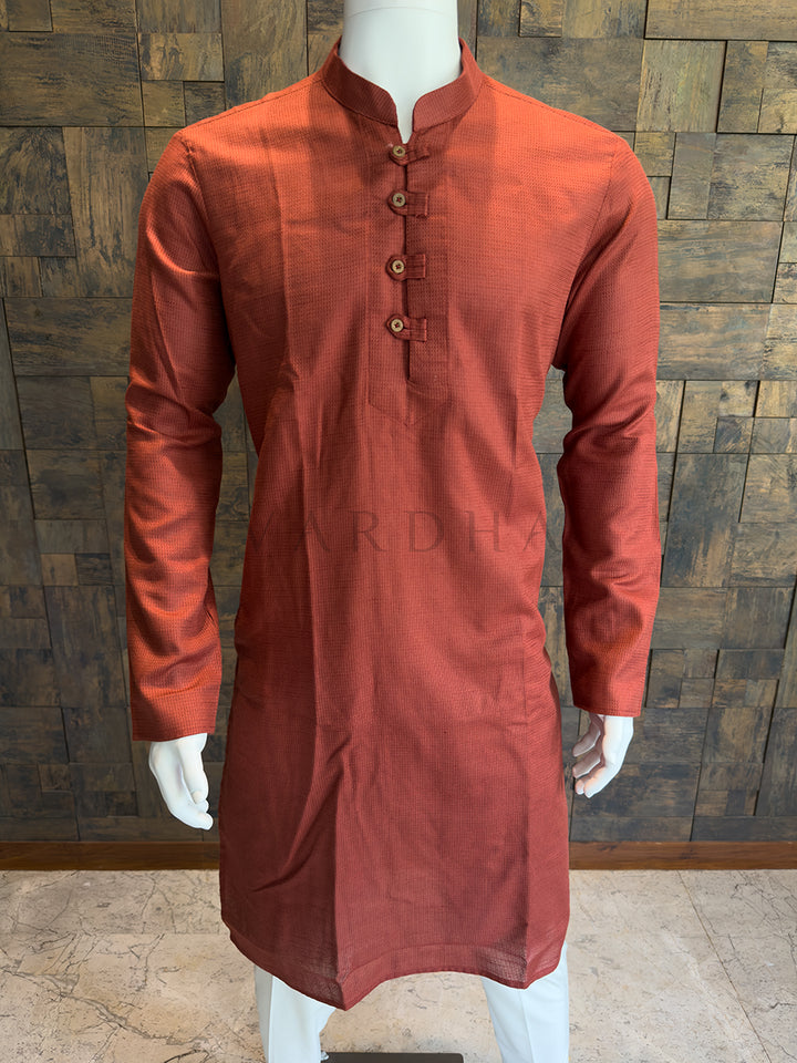 Orange kurta on a mannequin against a wooden paneled wall. Close-up of a designer rust orange kurta showing the distinct micro-check fabric pattern and rustic, artisanal wooden-style buttons.