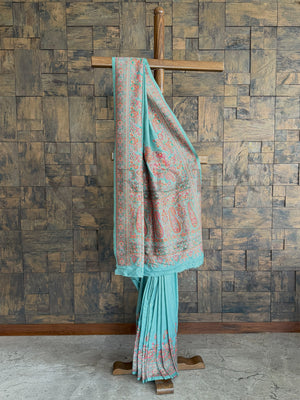 Graceful turquoise-blue Pashmina raw silk saree adorned with intricate embossed thread work, perfect for a sophisticated and timeless look.