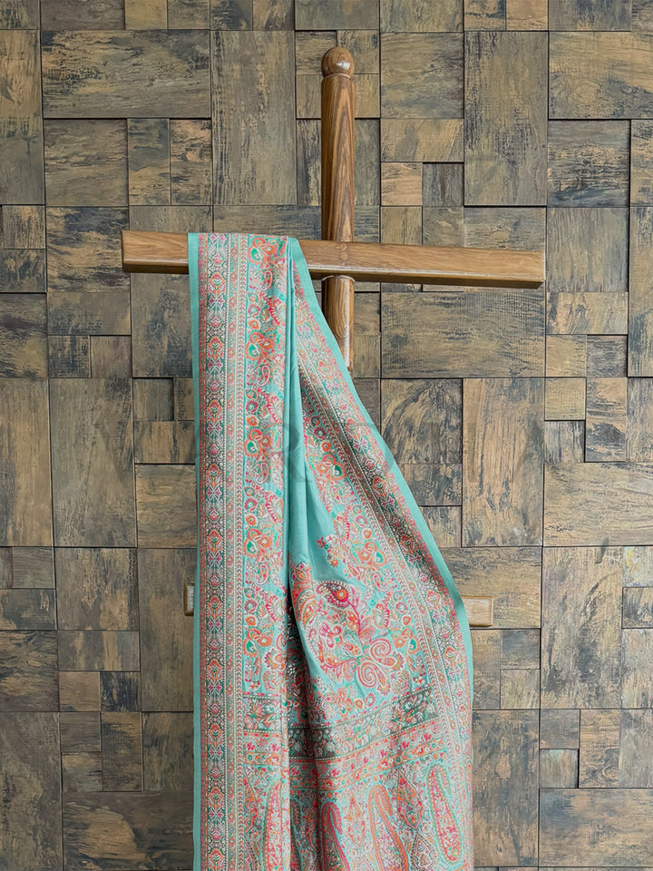 Luxurious turquoise-blue saree in Pashmina raw silk, featuring delicate embossed thread embroidery for an elegant appeal.