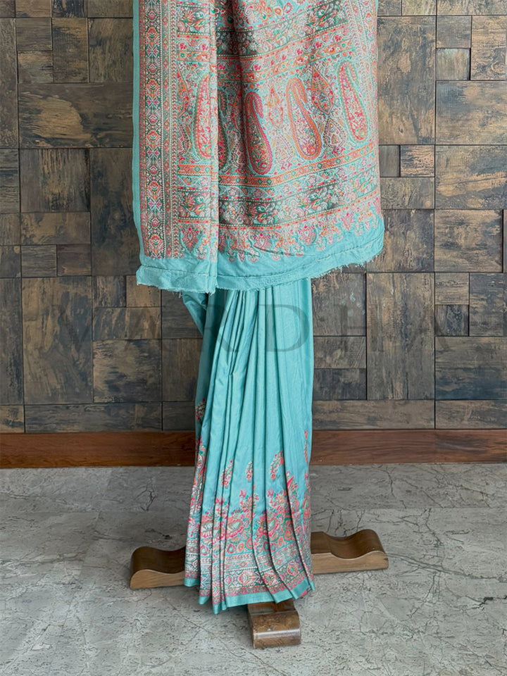 Stunning turquoise-blue Pashmina raw silk saree with fine embossed thread detailing, showcasing artisanal craftsmanship and refined beauty.